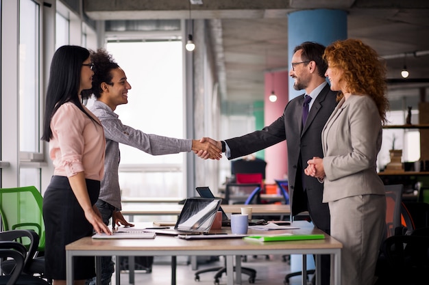 Equipos de negocios multiétnica en sala de reuniones dándose la mano.