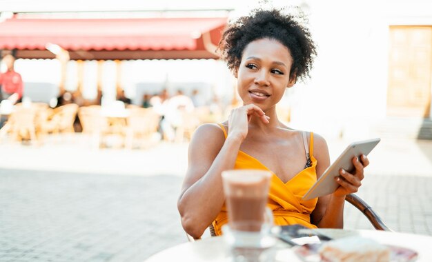 Er frühstückt in einem Café und arbeitet an einem Tablet. Macht eine Online-Bestellung im Online-Shop