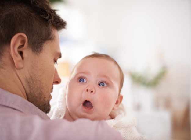 Er ist ein erstaunlicher Vater Ein süßes kleines Mädchen, das über die Schulter ihres Vaters schaut, während er sie hält