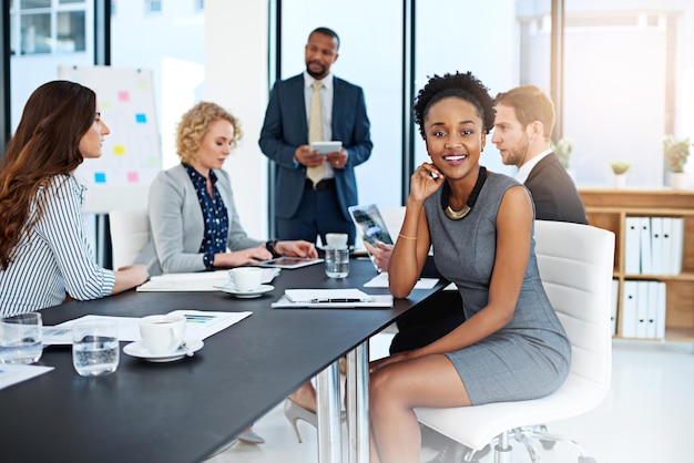 Era uma equipe de super-realizadores retrato de uma jovem empresária trabalhando na sala de reuniões com seus colegas em segundo plano