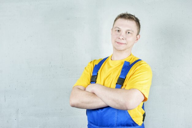 Erbauer in der Arbeitskleidung gegen eine graue Wand. Der Mann verschränkte die Arme vor der Brust.