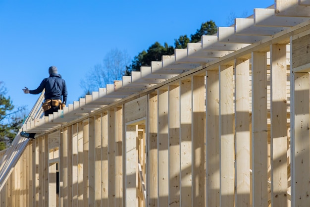 Erbauer innerhalb des hölzernen Hausmanns beim Nageln von Holzbalken arbeitet für den Bau mit einem Lufthammer von