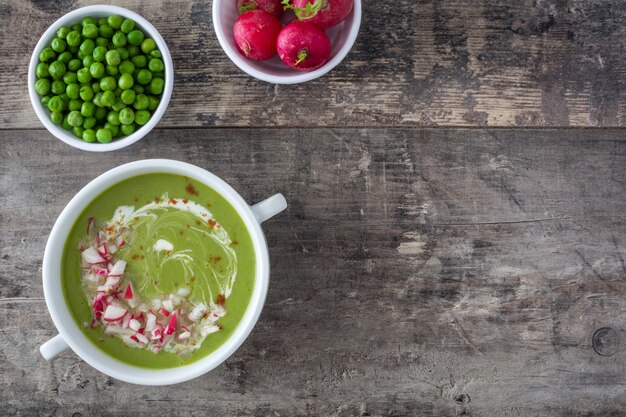 Erbsensuppe mit Radieschen auf rustikalem Holz Draufsicht