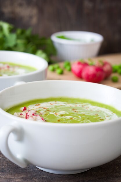 Erbsensuppe mit Radieschen auf rustikalem Holztisch