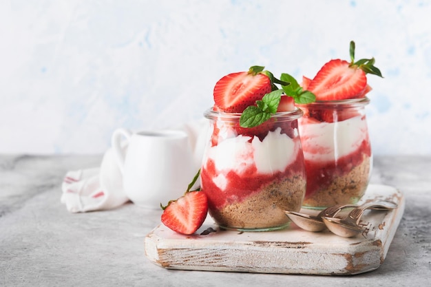 Erdbeer-Käsekuchen Käsekuchen oder Kleinigkeit mit Erdbeere im Glas auf alten grauen Beton Hintergrund Tabellenhintergrund Käsekuchen ohne Backen Dessert New York Textfreiraum Essen Hintergrund