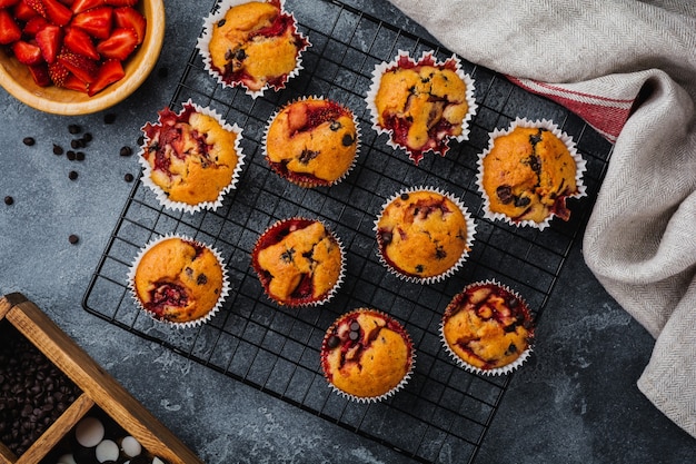 Erdbeer-Schokoladen-Cupcakes-Muffins auf altem Holzständer auf betongrauer Oberfläche