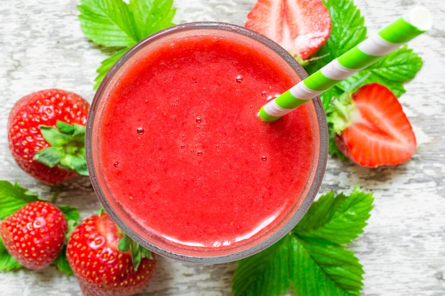 Erdbeer-Smoothie in einem Glas mit Stroh und frischen Beeren