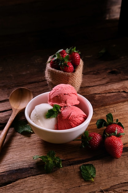 Foto erdbeer-vanille-eis im dunklen modus mit minzblättern