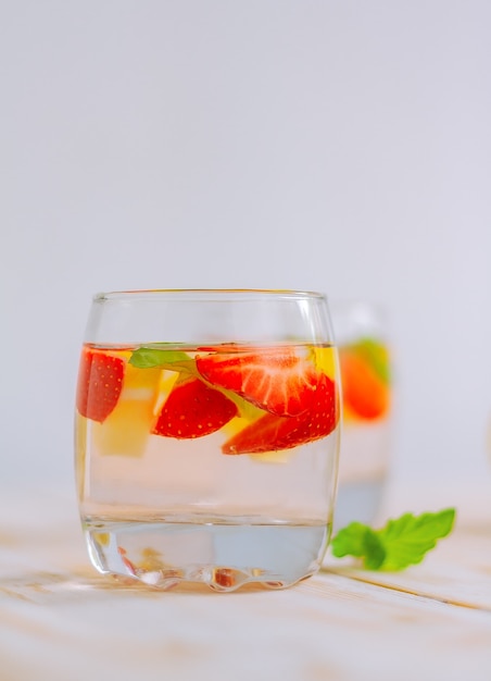 Erdbeer-Zitrus-Hausgemachtes Sommer-Erfrischungsgetränk. Zitronenwasser mit Beeren in einem Glas auf dem Tisch.