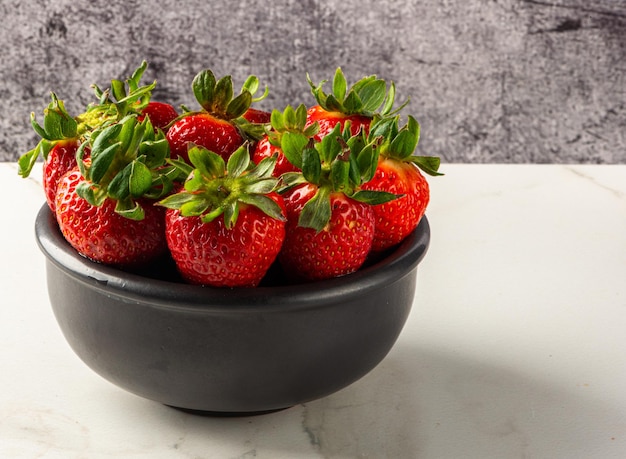 Erdbeerdessert serviert in einem Glas auf einem Holzbrett und frischem Obst auf Marmorhintergrund