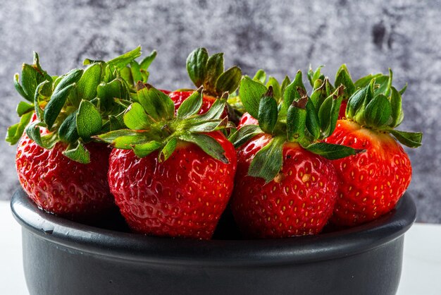 Erdbeerdessert serviert in einem Glas auf einem Holzbrett und frischem Obst auf Marmorhintergrund