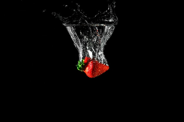 Erdbeere im Wasser mit schwarzem Hintergrund