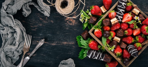 Erdbeere mit Schokolade in einer Holzkiste Auf einem hölzernen Hintergrund Ansicht von oben Kopieren Sie Platz