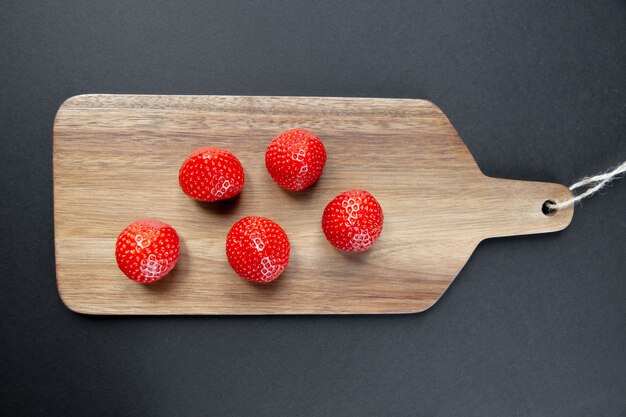 Erdbeeren auf einem Holzbrett. Schwarzer Hintergrund. Ansicht von oben