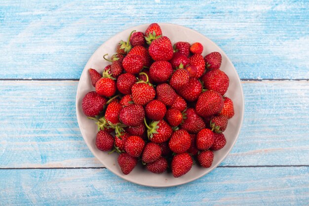 Erdbeeren auf einem Teller auf blauem Hintergrund aus Holz