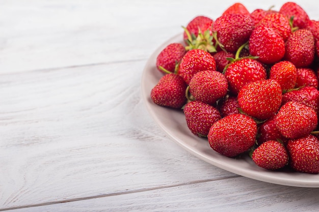 Erdbeeren auf einem Teller auf weißem Holzhintergrund