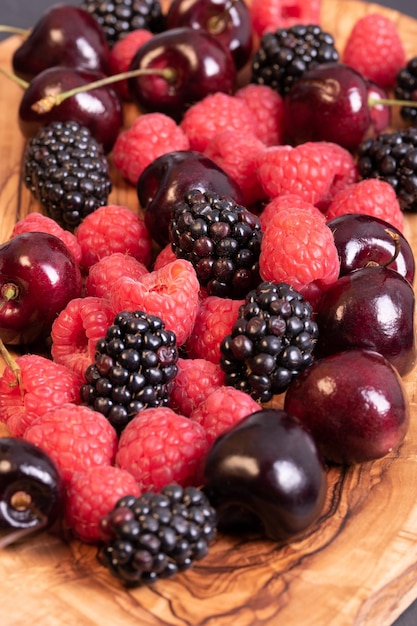 Erdbeeren, Brombeeren und Kirschen auf Schneidebrett aus Holz