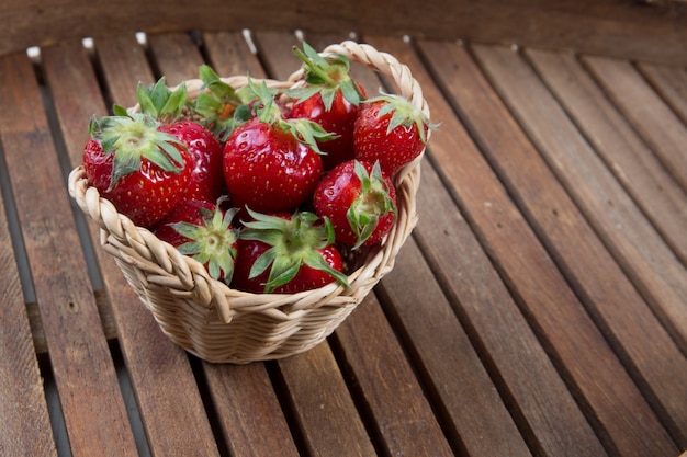 Erdbeeren im kleinen Korb unter hölzernem Hintergrund