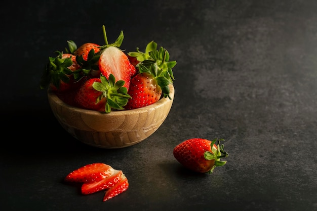 Erdbeeren in einem dunklen Hintergrund der hölzernen Schüssel