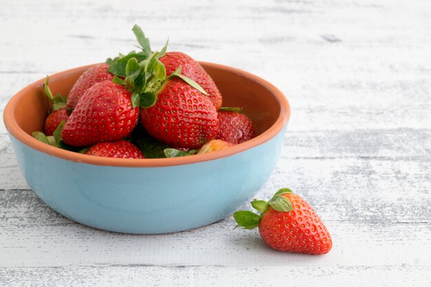 Erdbeeren in einer blauen Schüssel auf einem hellen Hintergrund.