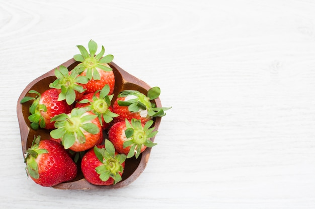 Erdbeeren in einer Schüssel auf weißem Holztisch. Draufsicht.