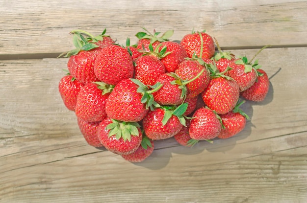 Erdbeeren in hölzernen Vintage-Tisch Frisch geerntete Erdbeeren auf dem Bauernmarkt Reife Erdbeeren auf einem hölzernen Hintergrund Freier Platz auf dem Tisch