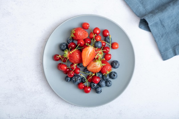 Erdbeeren, Kirschen und Blaubeeren auf einer Draufsicht der dunklen Platte