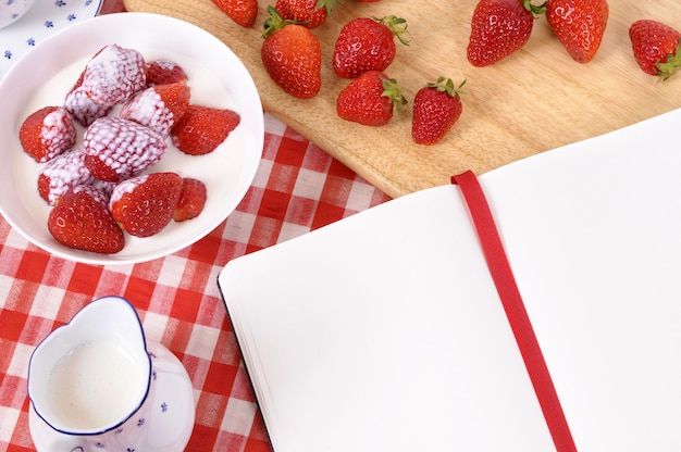 Erdbeeren mit leerem Rezeptbuch und Kontrolltischdecke