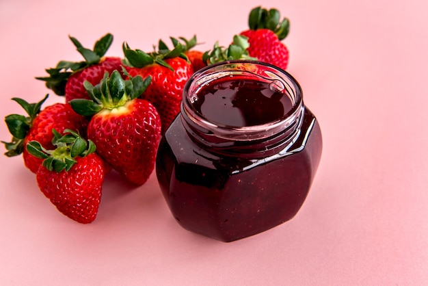 Erdbeeren und Erdbeermarmelade auf rosa Hintergrund