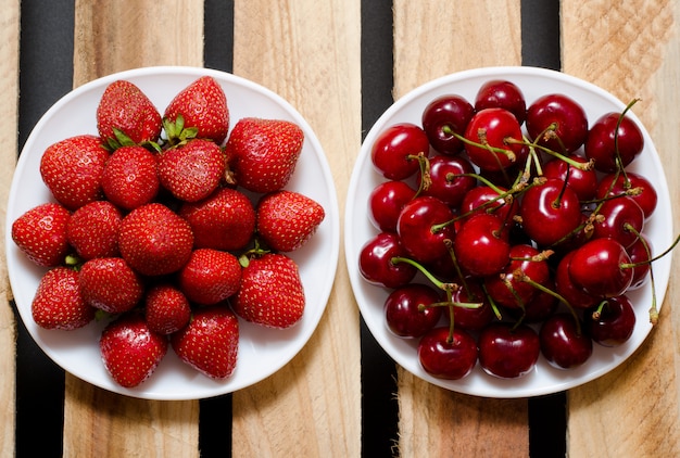 Erdbeeren und Kirschen in einer Platte auf einer hölzernen, Draufsicht