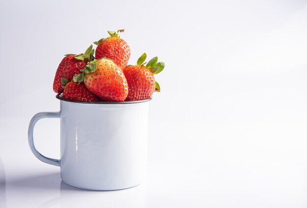 Erdbeeren, verschiedene schöne Erdbeeren in einem weißen Becher auf weißem Hintergrund, selektiver Fokus