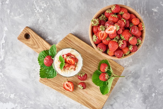 Erdbeergranola oder -smoothie in den Glas- und frischen Beeren in einer hölzernen Schüssel, Draufsicht. Gesundes Frühstück