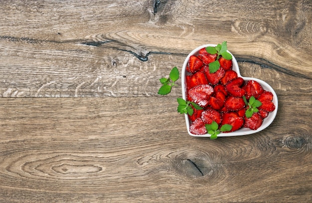 Foto erdbeerherz auf rustikalem hölzernem hintergrund lebensmittel-frucht-beeren