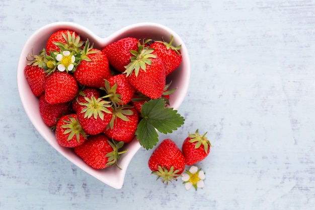 Erdbeerherz Frische Erdbeeren in Platte auf weißem Holztisch Draufsicht Kopienraum