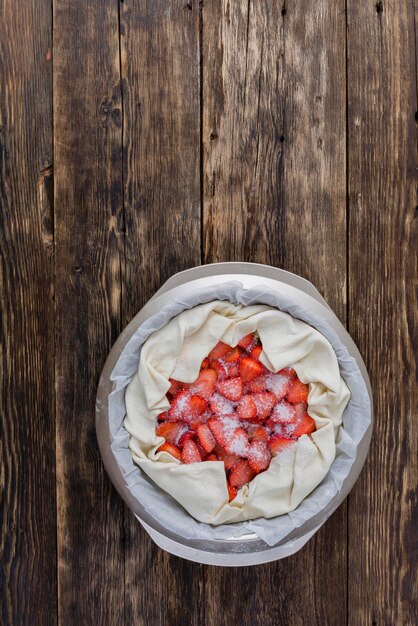 Erdbeerkuchen auf einem hölzernen Hintergrund kochen. Hausmannskost