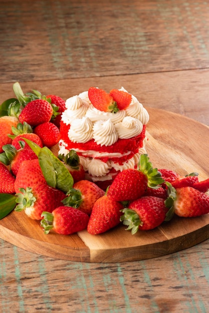 Erdbeerkuchen mit weißer Schokoladencreme und Erdbeeren auf rustikalem Tisch draußen