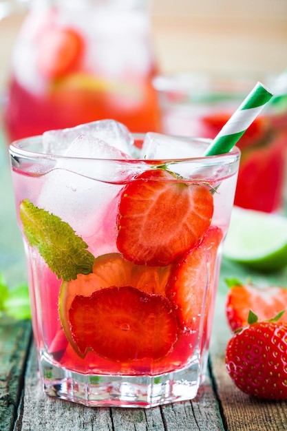 Erdbeerlimonade mit Kalk und Eis in einem Glas auf einem Holztisch