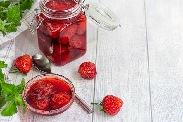 Erdbeermarmelade in einem Glas neben frischen Erdbeeren