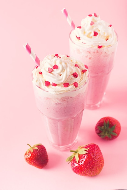 Erdbeermilchshake oder Smoothie und frische rohe Beeren auf rosa