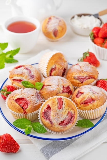 Erdbeermuffins oder Cupcakes auf einem Teller auf weißem Holzhintergrund Selektiver Fokus Nahaufnahme
