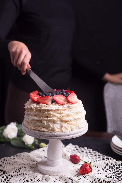 Erdbeerpavlova-Kuchen verziert von der Frau