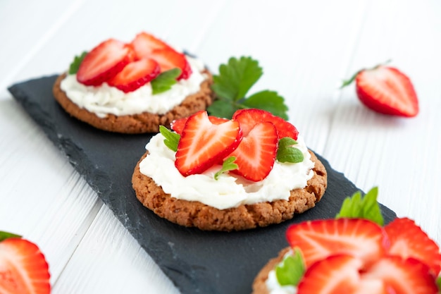 Erdbeertarte mit Haferkeks und Schlagsahne auf schwarzem Schieferbrett Rezept für einfachen Beerenkuchen zum Frühstück oder Urlaub Leichtes Sommerdessert