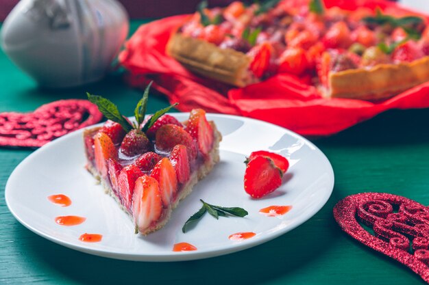 Erdbeertorte auf weißem Plattengrünholztisch. Ein Stück. Romantisch. Liebe. Herz. .