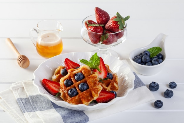 Erdbeerwaffeln und -blaubeeren mit Honig zum Frühstück