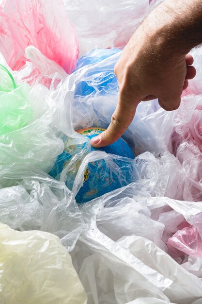 Erde berührt von einem Finger umgeben von Plastiktüten