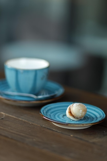 Erdnuss mit Kondensmilch Kekse mit Kondensmilch Blaue Tasse heißen Kaffee auf dem Hintergrund Selektiver Fokus auf Erdnuss mit verschwommenem Hintergrund