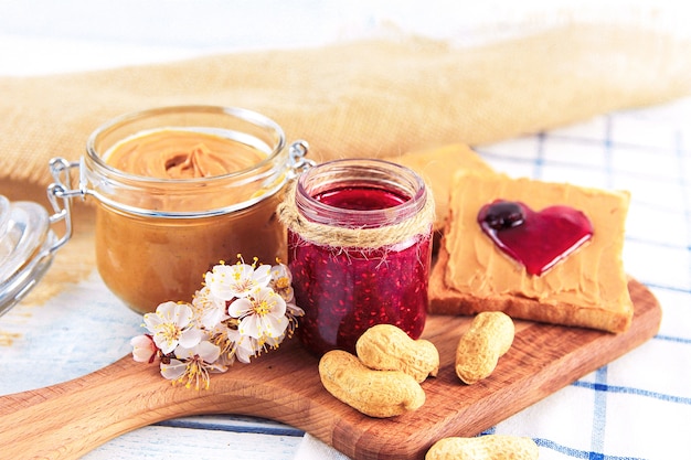 Erdnussbutter und Himbeermarmelade in der Nähe von Erdnüssen