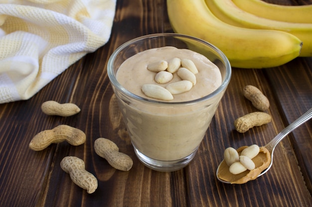 Erdnussbutterbananenshake im Glas auf dem braunen hölzernen Hintergrund