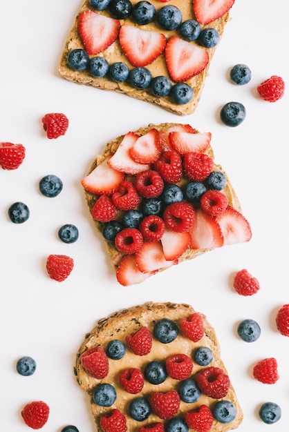 Erdnussbuttertoast mit Vollkornbrot Blaubeere Erdbeere und Himbeere auf weißem Hintergrund