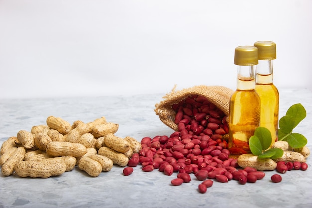 Erdnussölfläschchen mit Erdnüssen in der Schale und in Bio-Körnern